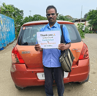a man holding a thank you sign in front of his car